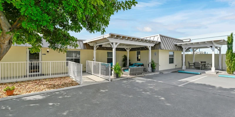 Front entrance with covered seating area and white railings.