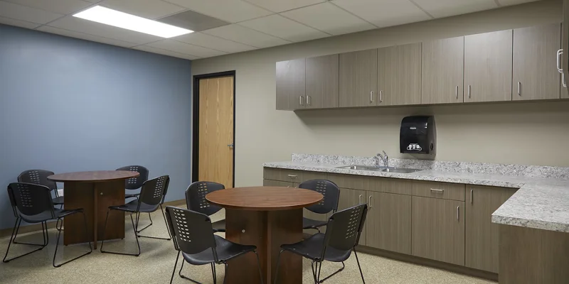 Break room with tables, chairs, and a kitchenette.