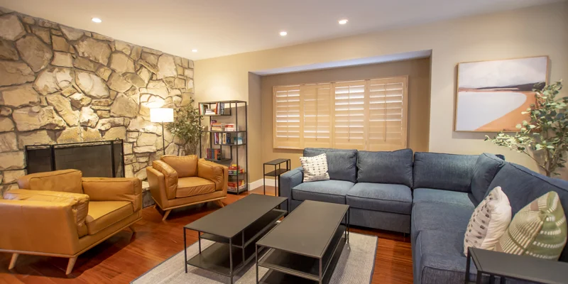 Living room with a stone fireplace, blue sectional, and leather chairs