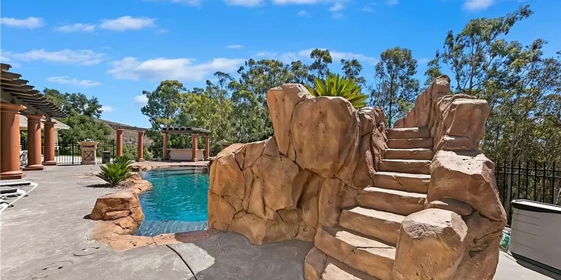 Covered patio with chairs and a pool.
