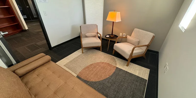 Small therapy room with beige chairs and a cozy atmosphere.