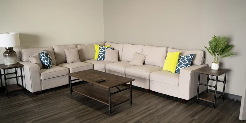  lounge area with a beige couch, wooden tables, and a modern design.