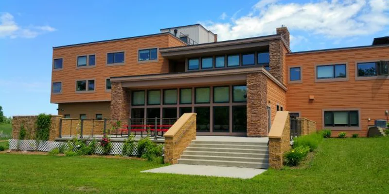 Exterior view of the rehab facility with stairs to entrance on a lawn.