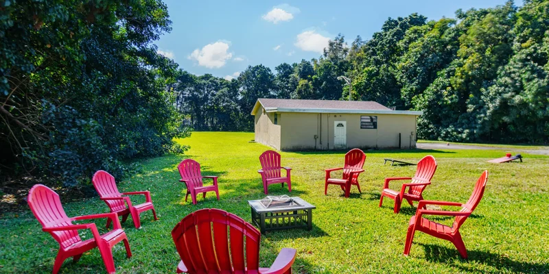 Red chairs in a circle around a firepit on grass