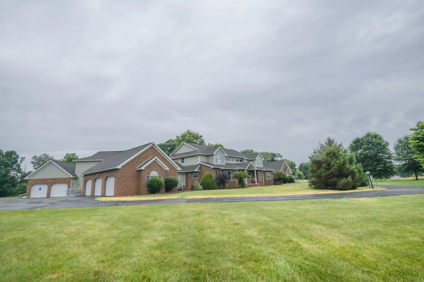 Side view of a rehab facility with a large lawn and driveway.