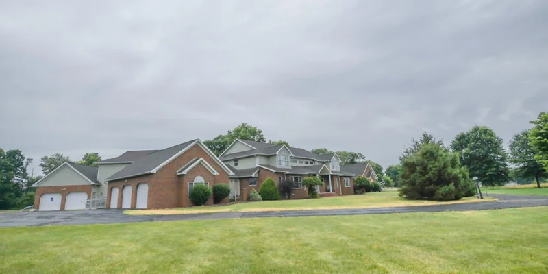 Side view of a rehab facility with a large lawn and driveway.