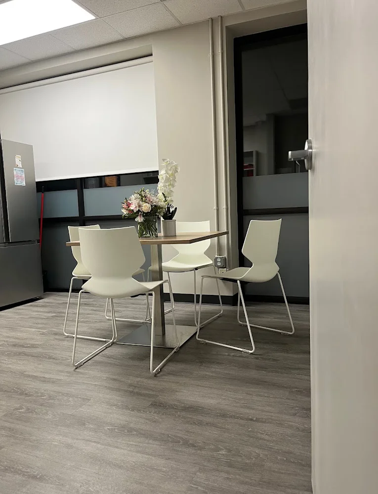 A small dining area with a table and white chairs.