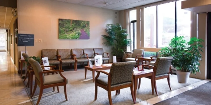 A spacious waiting room with chairs, tables, and large windows.