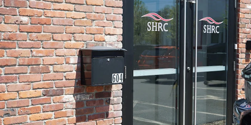 Outdoor view of building’s entrance with parking lot. ​​