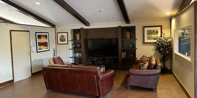 Lounge area with leather couches, TV, and wall decor.