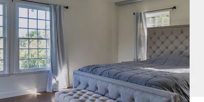 Private bedroom with a bed and ottoman.