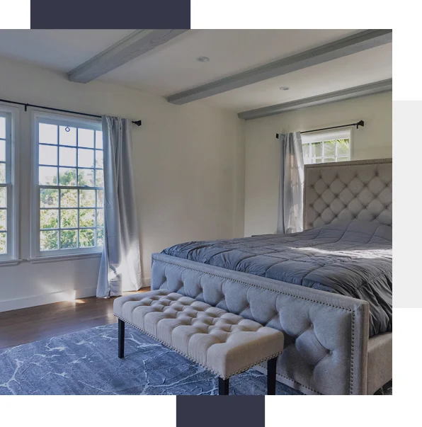 Private bedroom with a bed and ottoman.