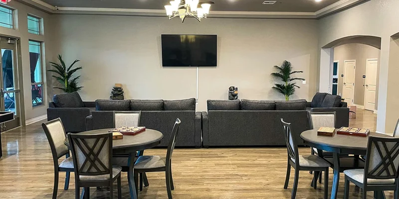 Lounge with sofas and circular tables in front of a TV.