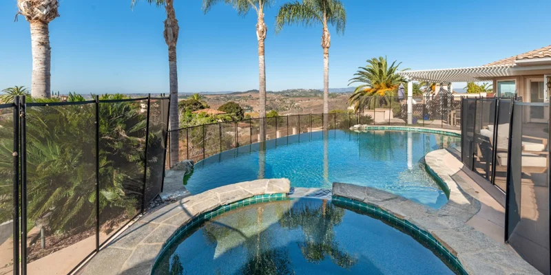 Outdoor recreation space with pools, palm trees and hillside view.