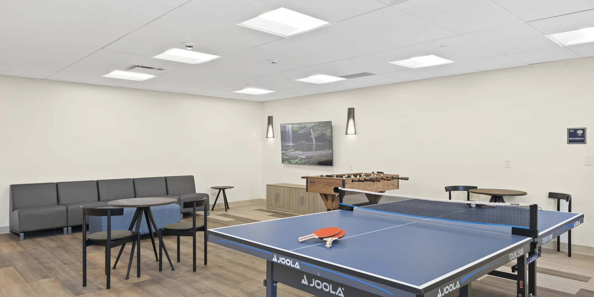 A recreation room with a ping pong table and seating.