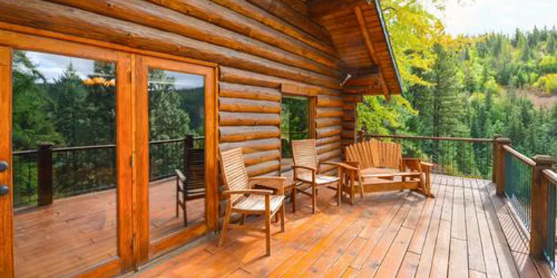 Outdoor wooden deck with seating overlooking a forest view.