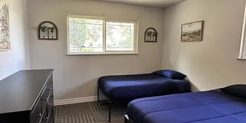 Shared bedroom with two beds, bright walls, and minimal furnishings.