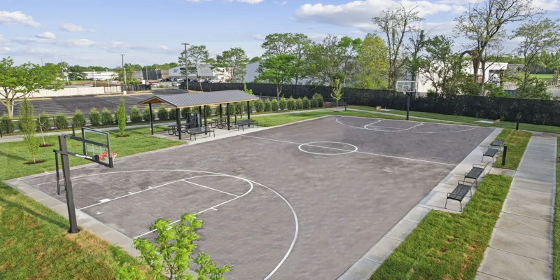 An outdoor basketball court with a covered seating area.