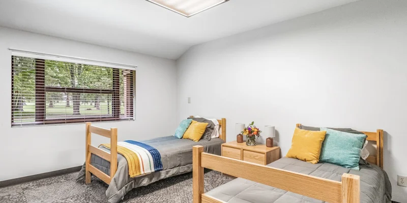 Shared bedroom with two twin beds and colorful pillows.