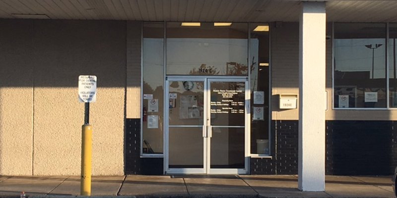 The entrance of a treatment center with glass doors and posted notices.