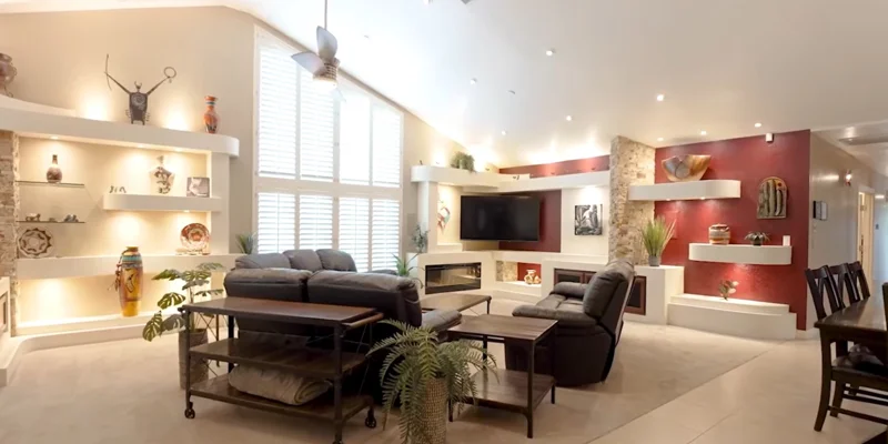 Lounge area with black couches, TV, and windows.
