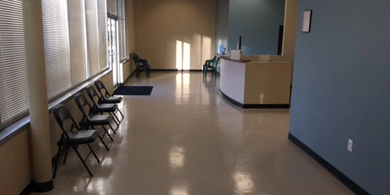 A waiting area with chairs along the window and a reception desk.