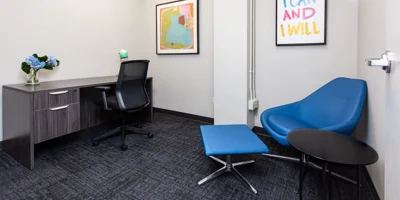 A small office with blue chairs and modern wall art.