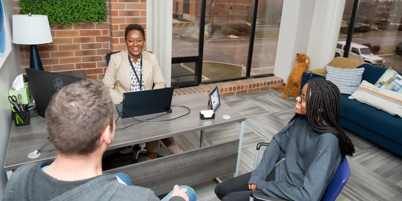 Three people having a conversation in a counseling room.