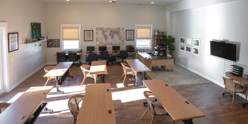 Classroom with ample natural light, with several desks.