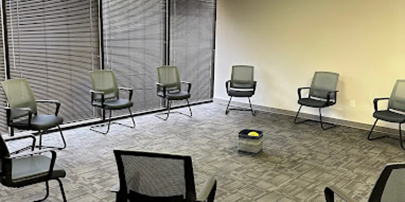 A group therapy room with chairs arranged in a circle near large windows.