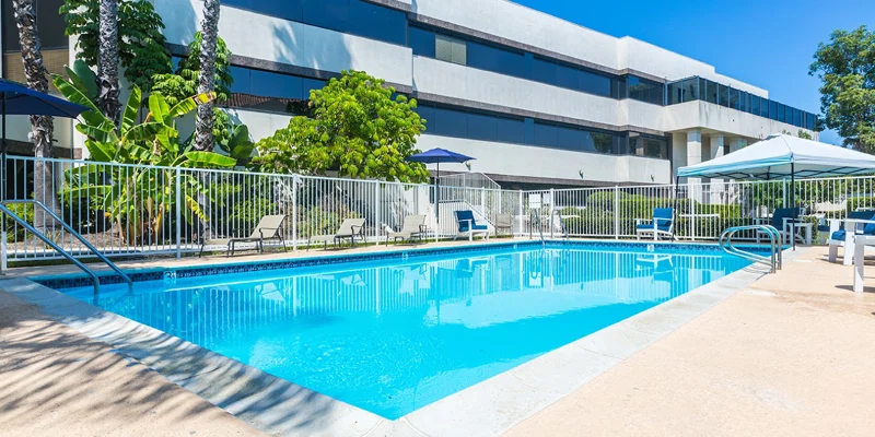 An outdoor pool area with lounge chairs and tropical plants