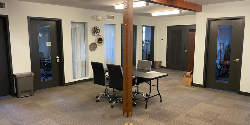 Open workspace with desks, chairs, and a wooden beam