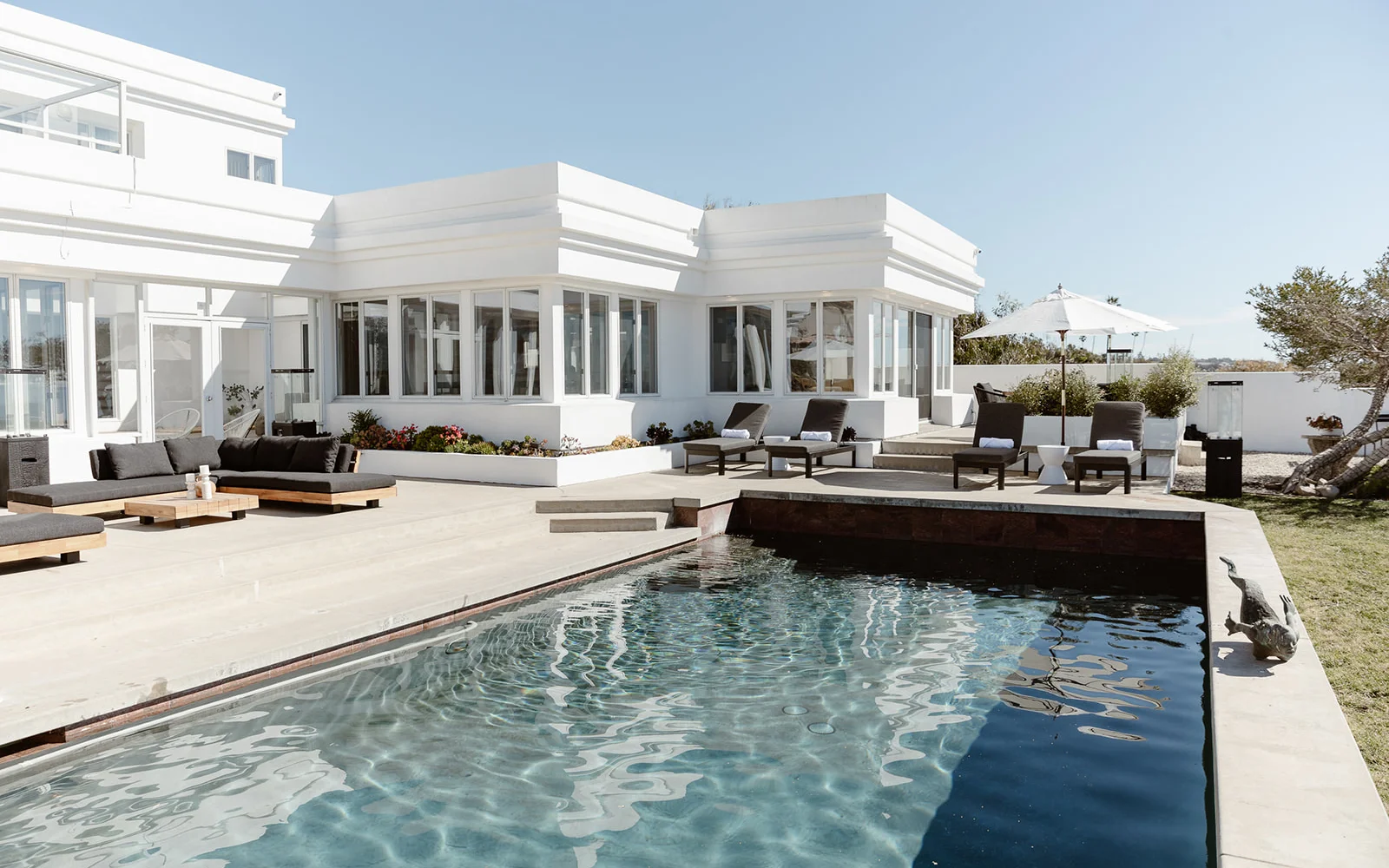  Modern poolside patio with black lounge chairs and ocean views.