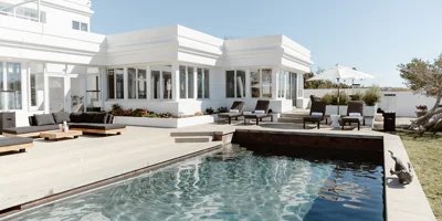  Modern poolside patio with black lounge chairs and ocean views.