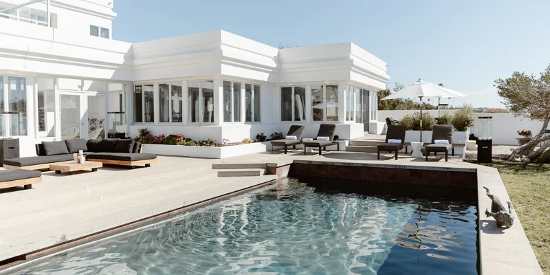  Modern poolside patio with black lounge chairs and ocean views.