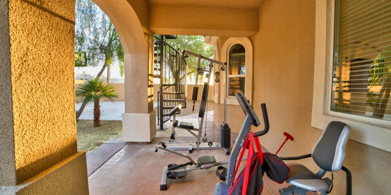 Gym area with fitness equipment under a covered patio.