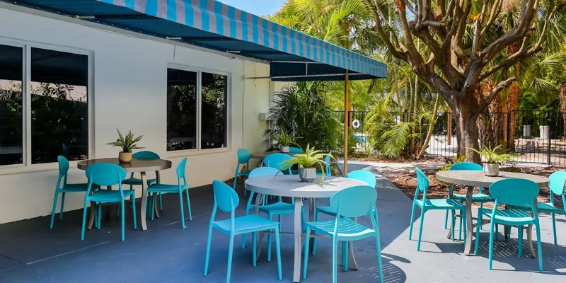 Outdoor dining area with blue chairs and shaded awning