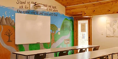 A warm classroom with wooden walls and a mural.
