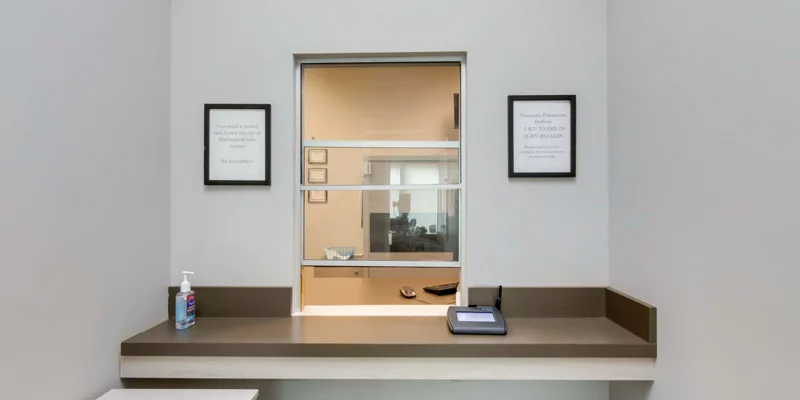 Reception window with signs and a bin.