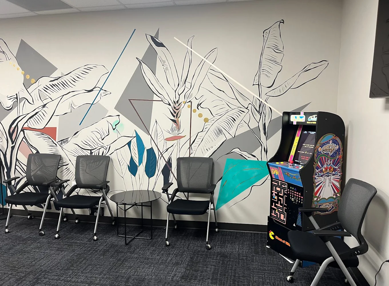 A lounge with modern art, chairs, and an arcade game.