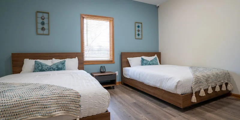 Bedroom with two beds, blue accent wall, and modern decor.