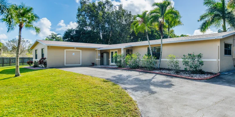 Single-story facility with driveway and palm trees