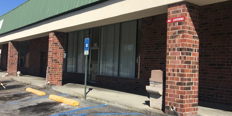 Exterior of a rehab facility with brick columns and a green awning.