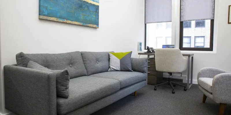 Office with gray couch and desk.