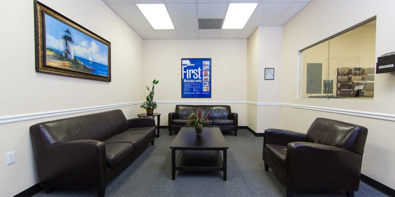 Lounge area with brown leather couches and framed wall art.