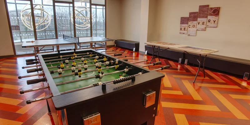 Recreation room with a pingpong and foosball table with seating along wall.
