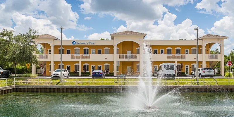Two-story treatment facility with a fountain and parking area.