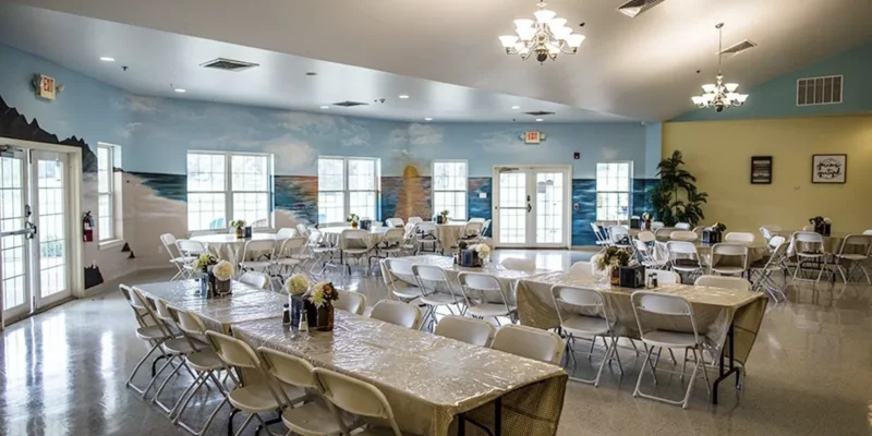 A spacious dining hall with tables, chairs, and a mural on the wall.