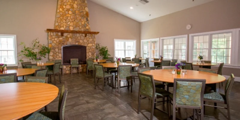 A dining area with round tables, chairs, and a stone fireplace.