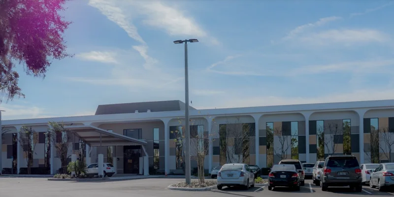 A spacious rehab facility exterior with a parking lot and modern design.